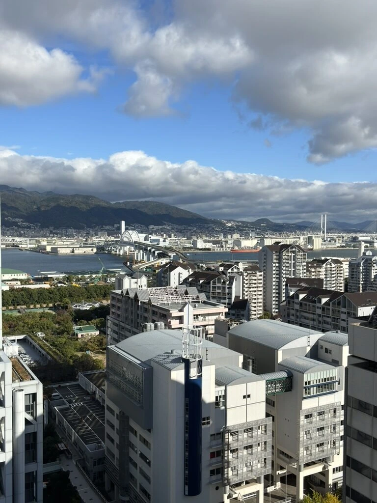 翌朝の窓からの眺め。青空と六甲アイランドの建物、奥に神戸の港と山