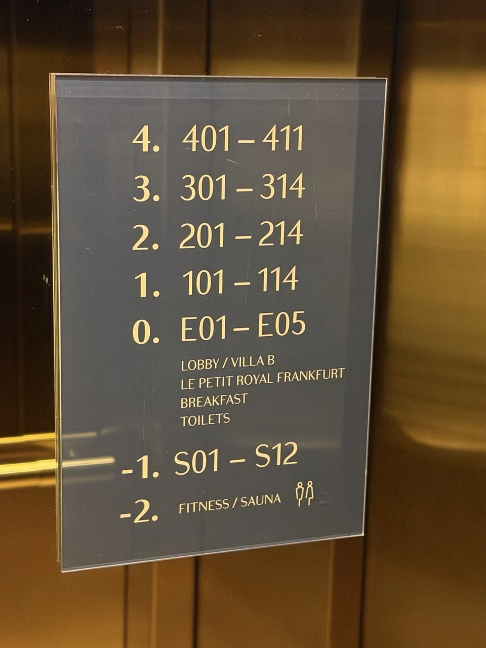LUME Boutique Hotelのエレベーター内のフロア案内。4階から1階の客室番号、0階のロビーとLE PETIT ROYAL FRANKFURTと朝食、地下1階の客室、地下2階のフィットネスとサウナ