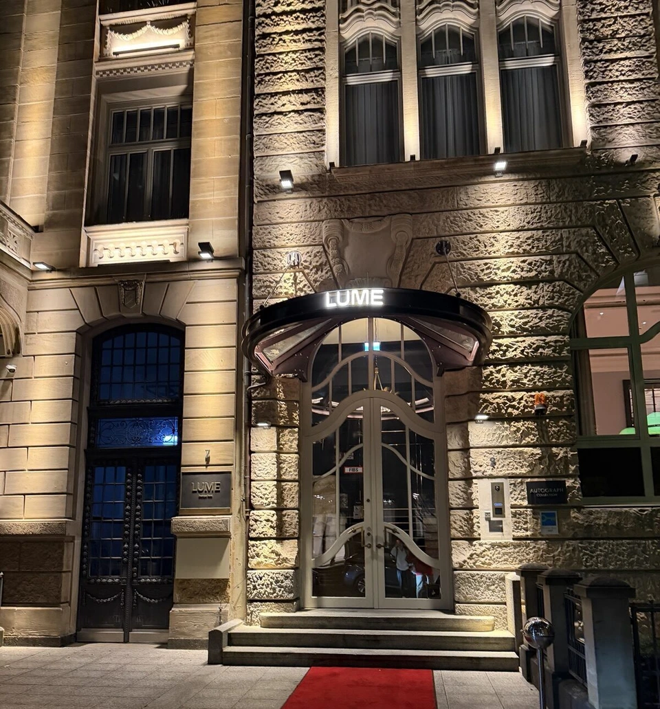 夜のLUME Boutique Hotelの入口。ライトアップされた石の外壁と、LUMEの文字が光るガラスのひさし、赤いじゅうたん