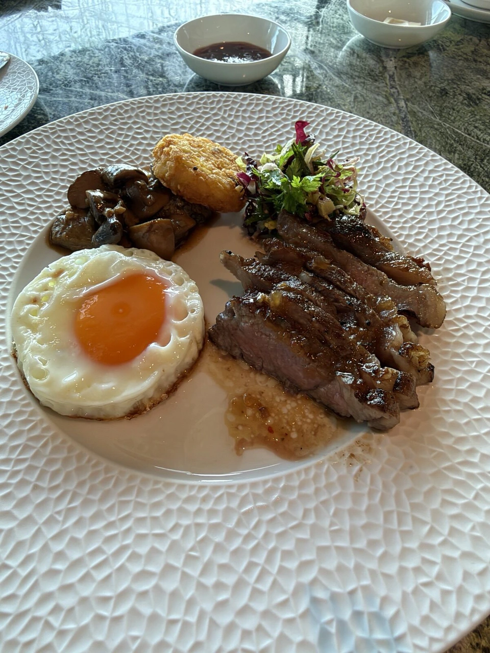 マンダイ・レインフォレスト・リゾートの朝食のメイン。スライスしたステーキ、目玉焼き、ハッシュブラウン、キノコのソテー