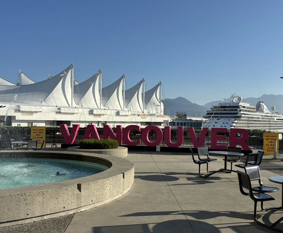 朝のカナダプレイス。白い帆の形の屋根と、ピンク色のVANCOUVERの文字、奥に停泊する大きなクルーズ船