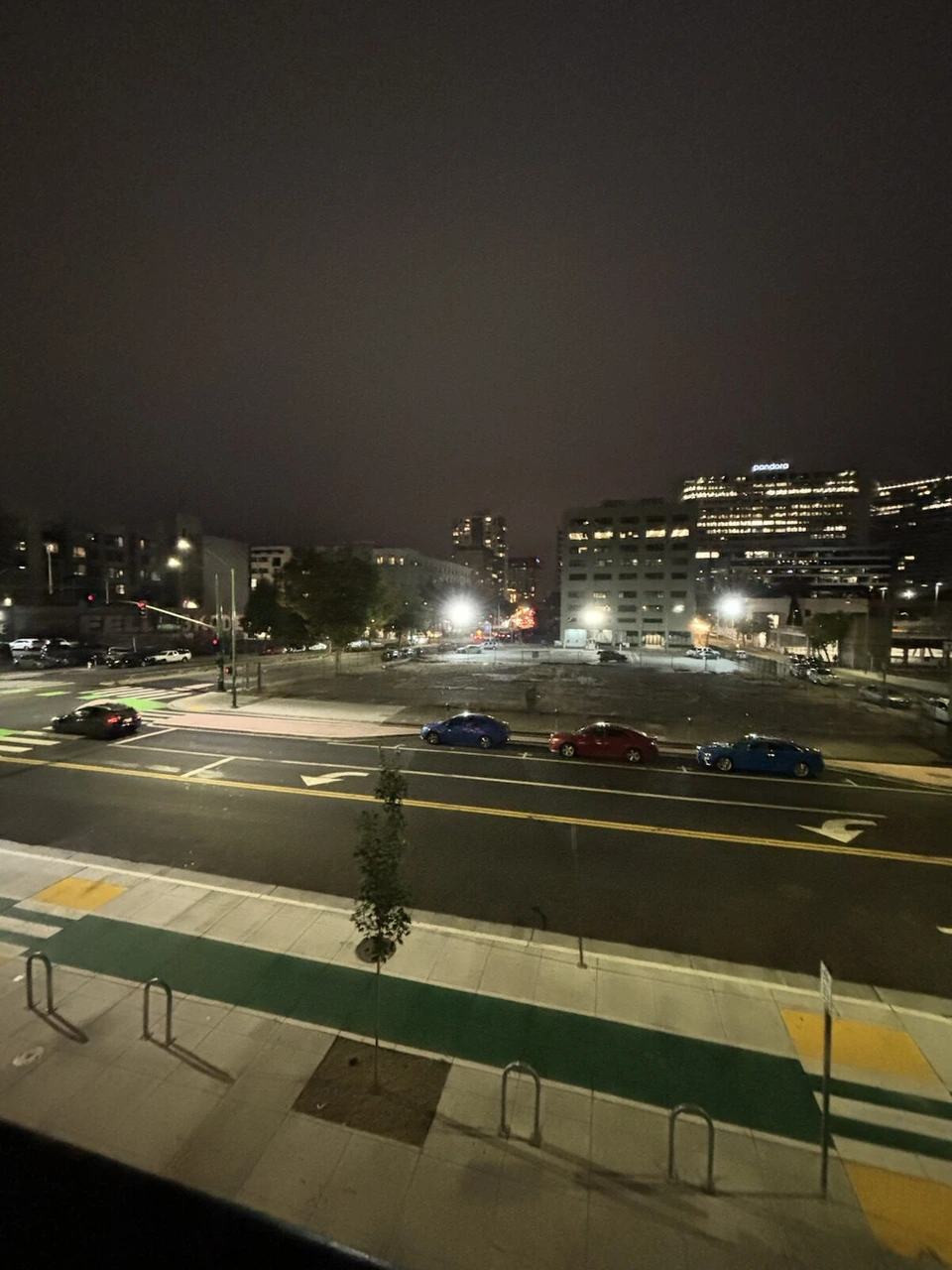 モクシー・オークランド・ダウンタウンのテラスから見た夜の大通りと駐車場、奥のオフィスビルの明かり