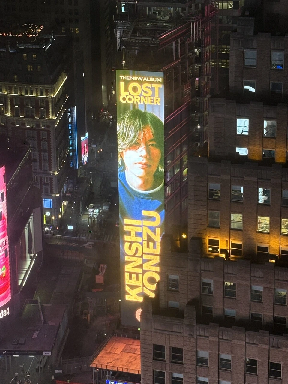 客室から見た夜のビルの壁の米津玄師のアルバムLOST CORNERの縦長の広告