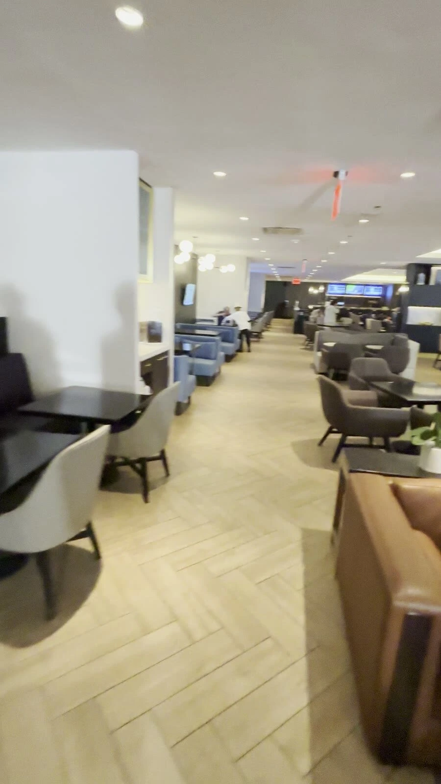 M Clubの中。木目の床の通路の両側に、青いソファ席とグレーの1人掛けの椅子が奥まで並ぶ