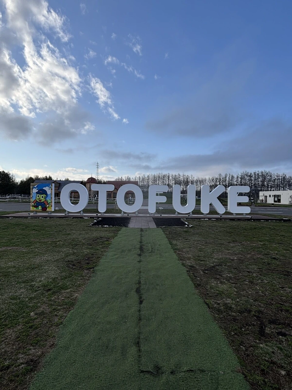 青空の下に立つ白い「OTOFUKE」の文字のオブジェ