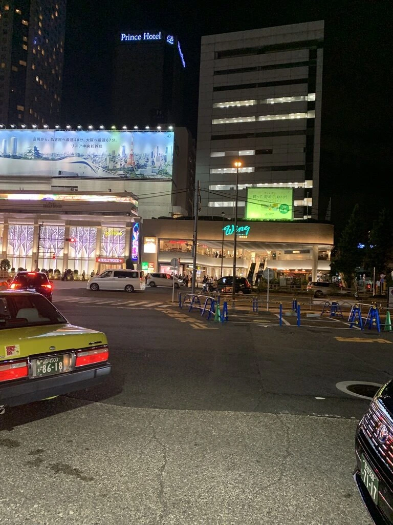 ホテル日航つくばへ向かう途中の夜の品川駅前。明るいホテルの看板とタクシー