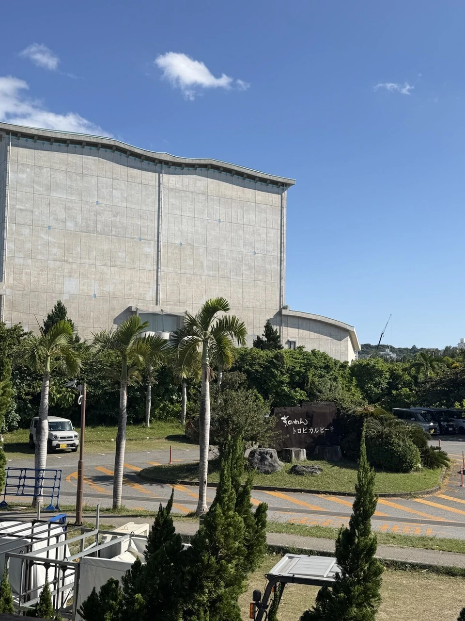 ぎのわんトロピカルビーチの石の看板と、奥の沖縄コンベンションセンター展示棟の大きな壁