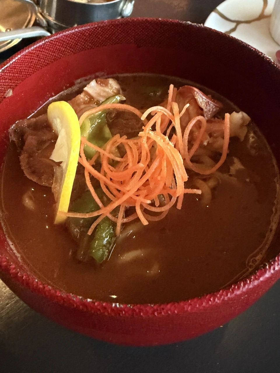 大阪ステーションホテルのSPECIALTY SALONの赤い器に入った、肉と野菜の温かい煮込み。上に細切りのにんじんとレモン