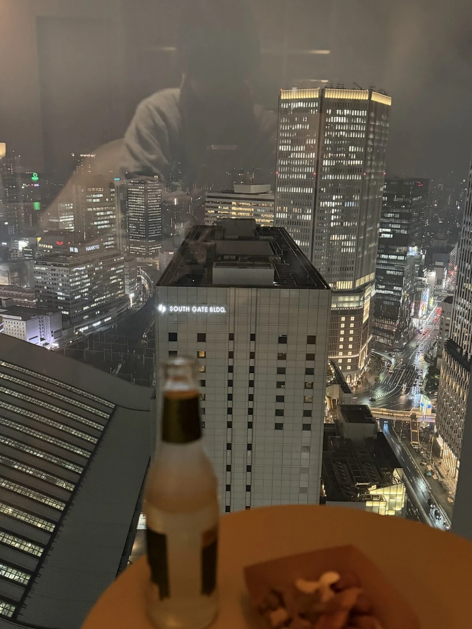 大阪ステーションホテルの夜の窓辺の飲み物とライトアップされた梅田のビル