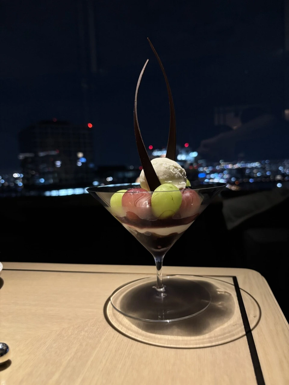 大阪ステーションホテルの夜景を背にしたぶどうとアイスのパフェ