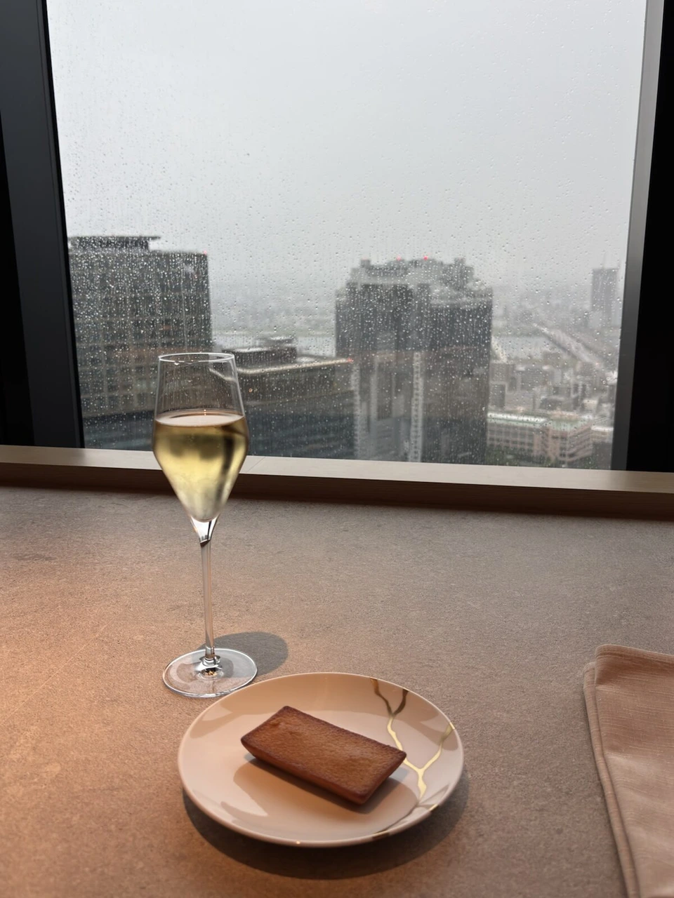 大阪ステーションホテルの雨の窓際の席に置かれたシャンパンと焼き菓子