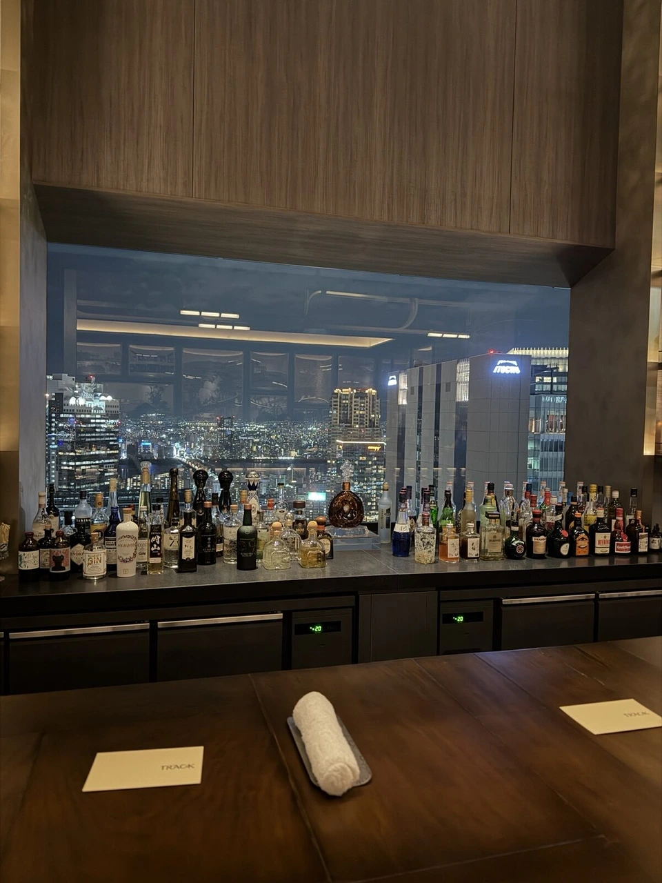 大阪ステーションホテルの夜景が見えるバーのカウンターと酒瓶の棚
