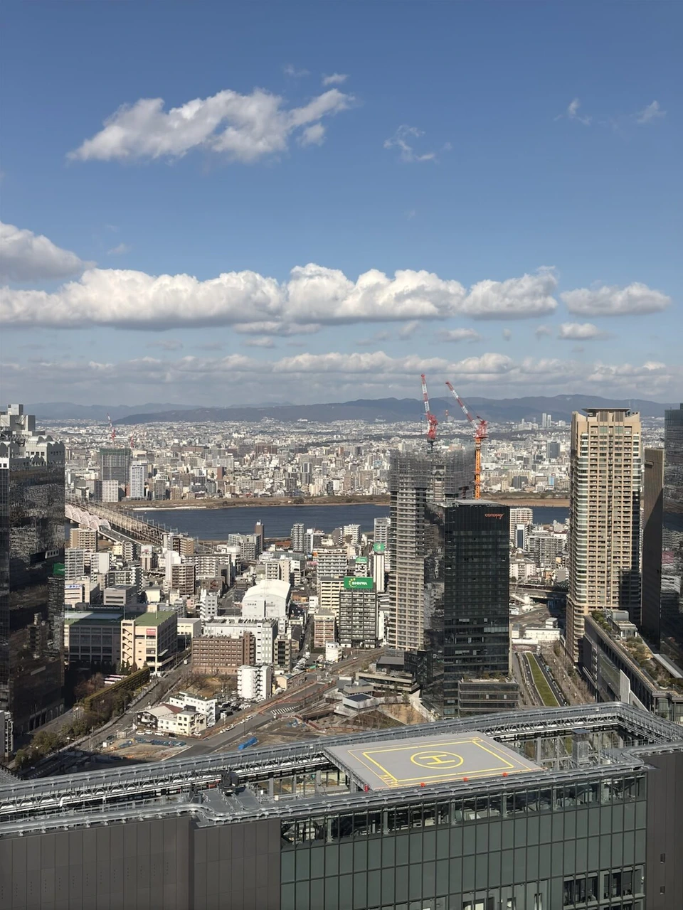 大阪ステーションホテルの晴れた昼のコーナールームの窓から見た梅田のビル群と淀川方面