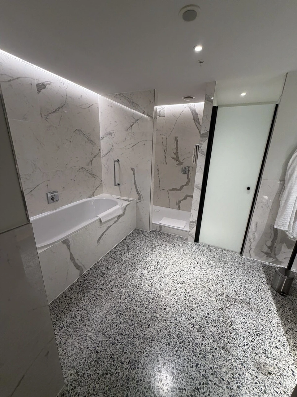 バスルームのバスタブとシャワー、黒い枠のトイレの扉