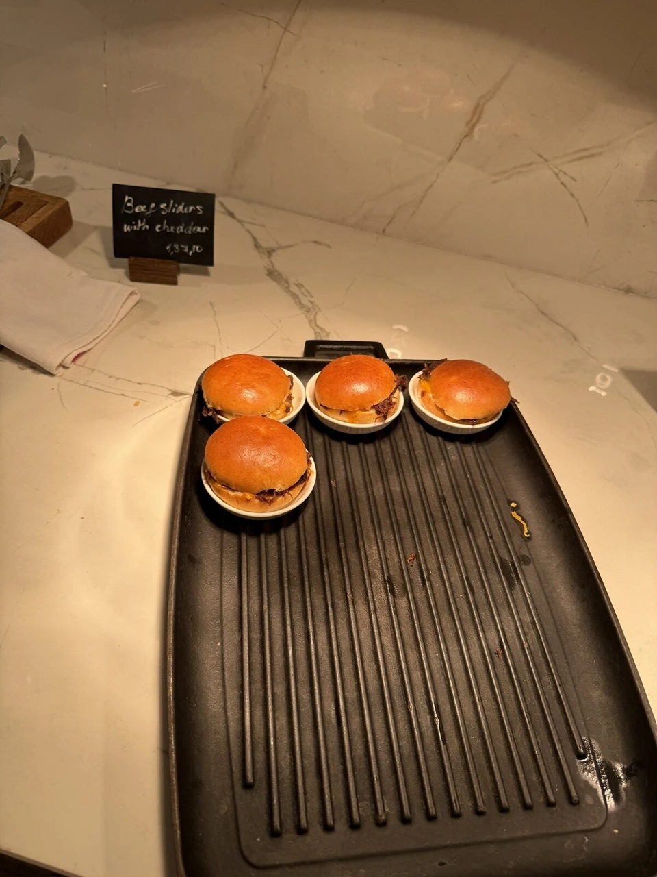 M Clubの夜の料理。鉄板のプレートにのったビーフスライダー4個