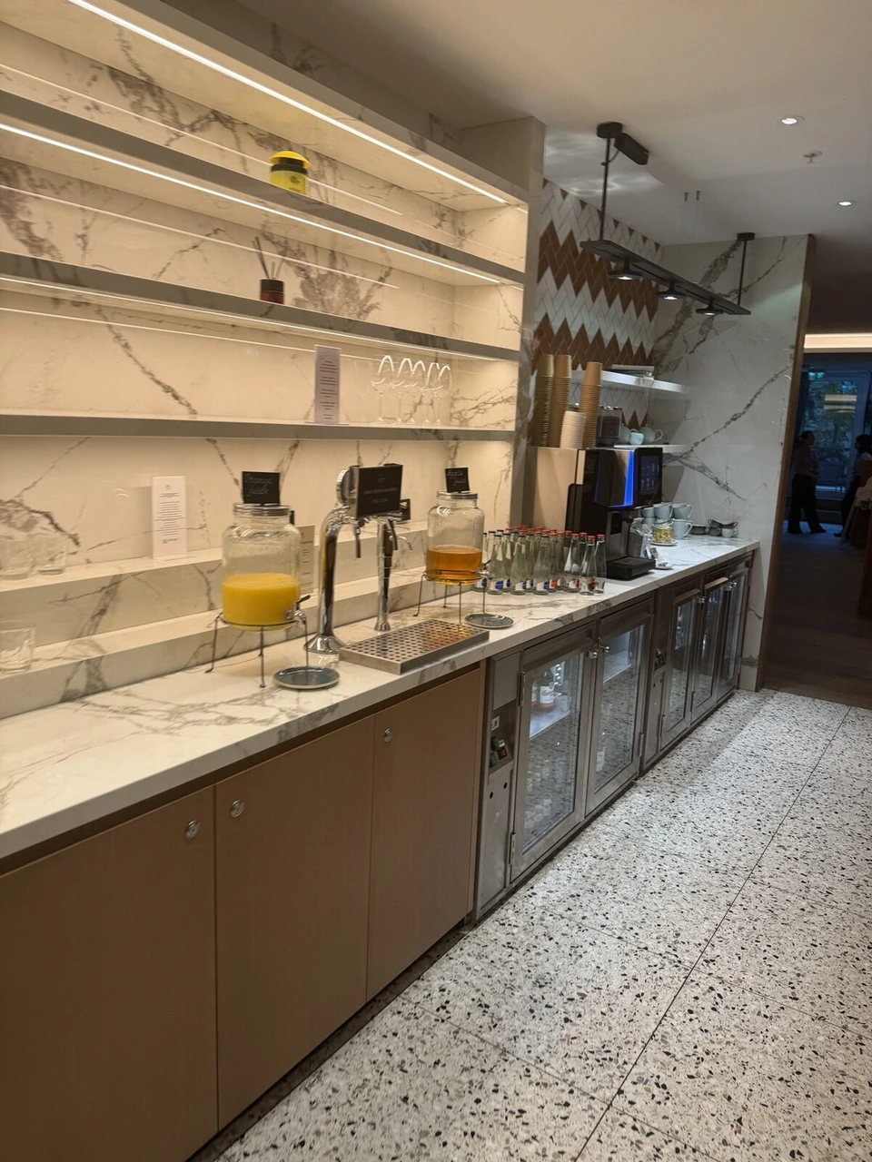 M Clubの飲み物のカウンター。ジュースのディスペンサー、コーヒーマシン、冷蔵庫