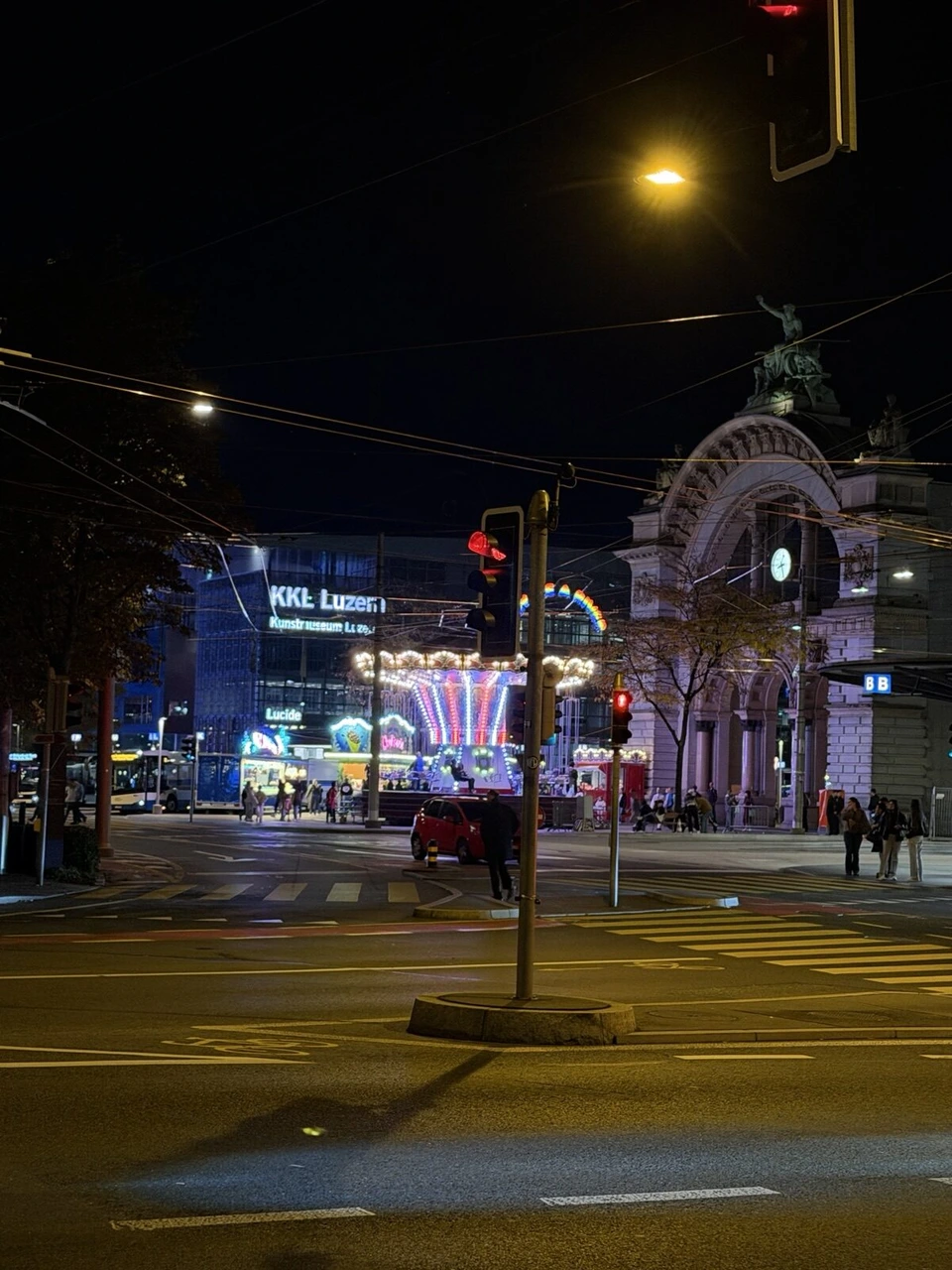 夜のルツェルン駅前。ライトアップされた旧駅舎の門と、KKLルツェルンの建物
