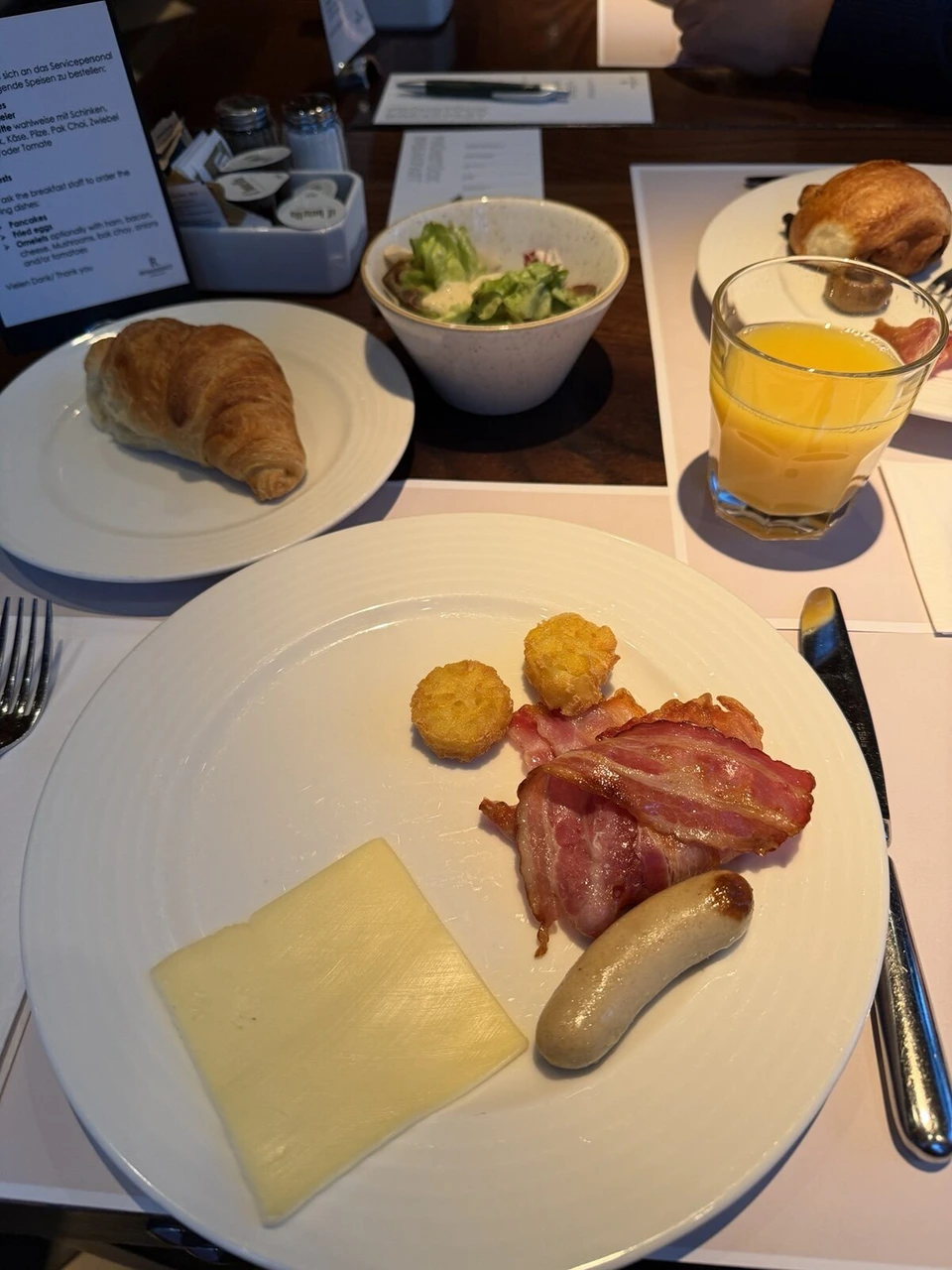 ルネッサンス・ルツェルン・ホテルの朝食。チーズ、ベーコン、ソーセージ、ポテト、クロワッサン、サラダ、オレンジジュース