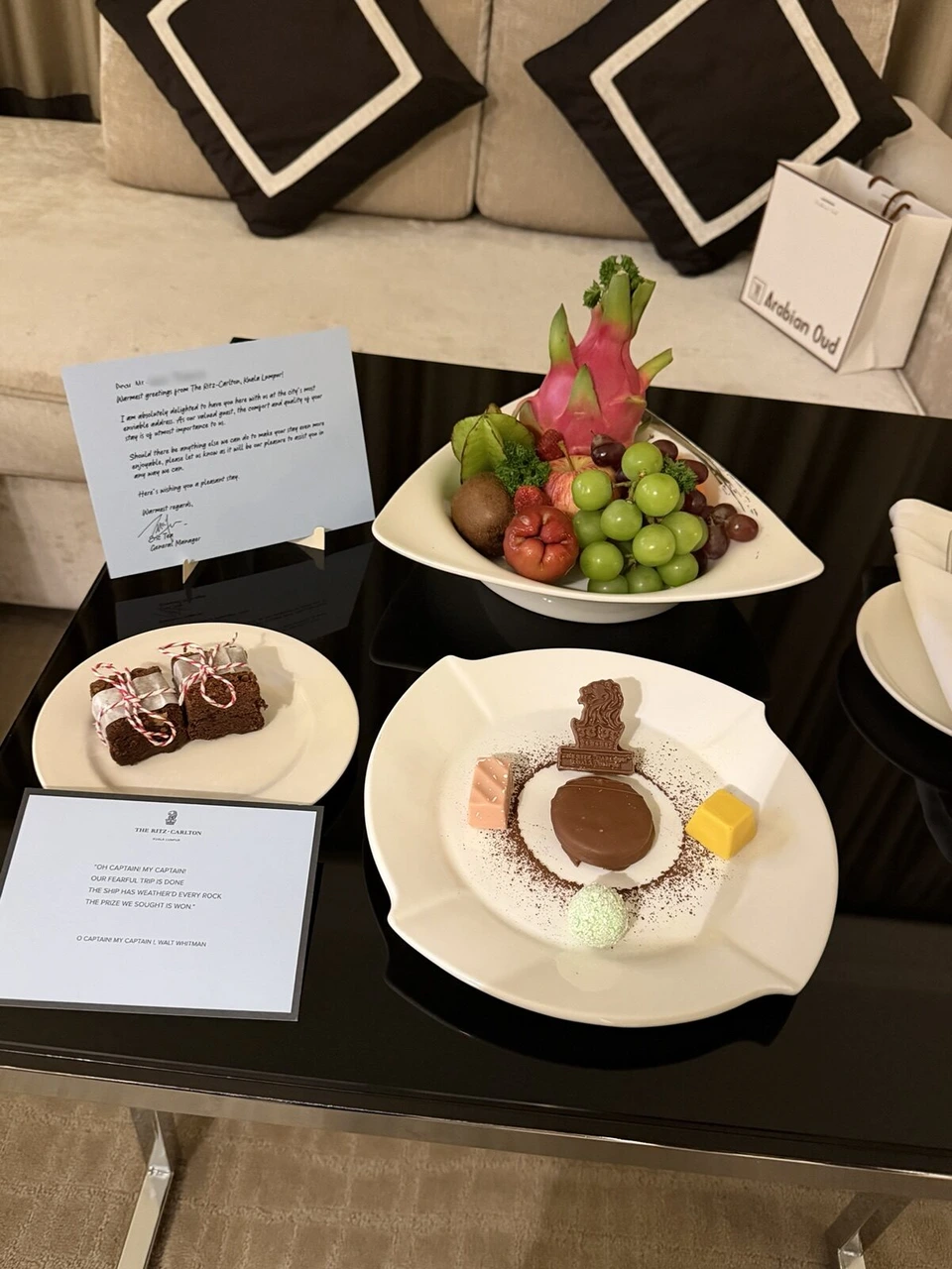ターンダウン後の客室のテーブル。フルーツの盛り合わせ、ライオンの形のチョコレートを添えたデザート、ブラウニー