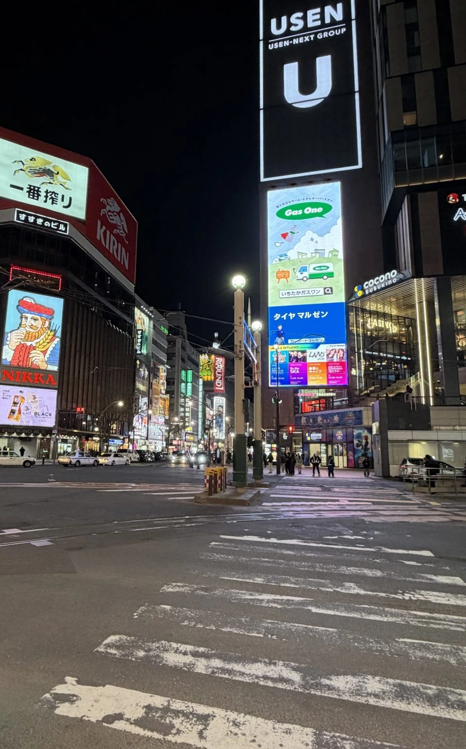 夜のすすきの交差点。キリンの看板やネオンの広告が並ぶビル