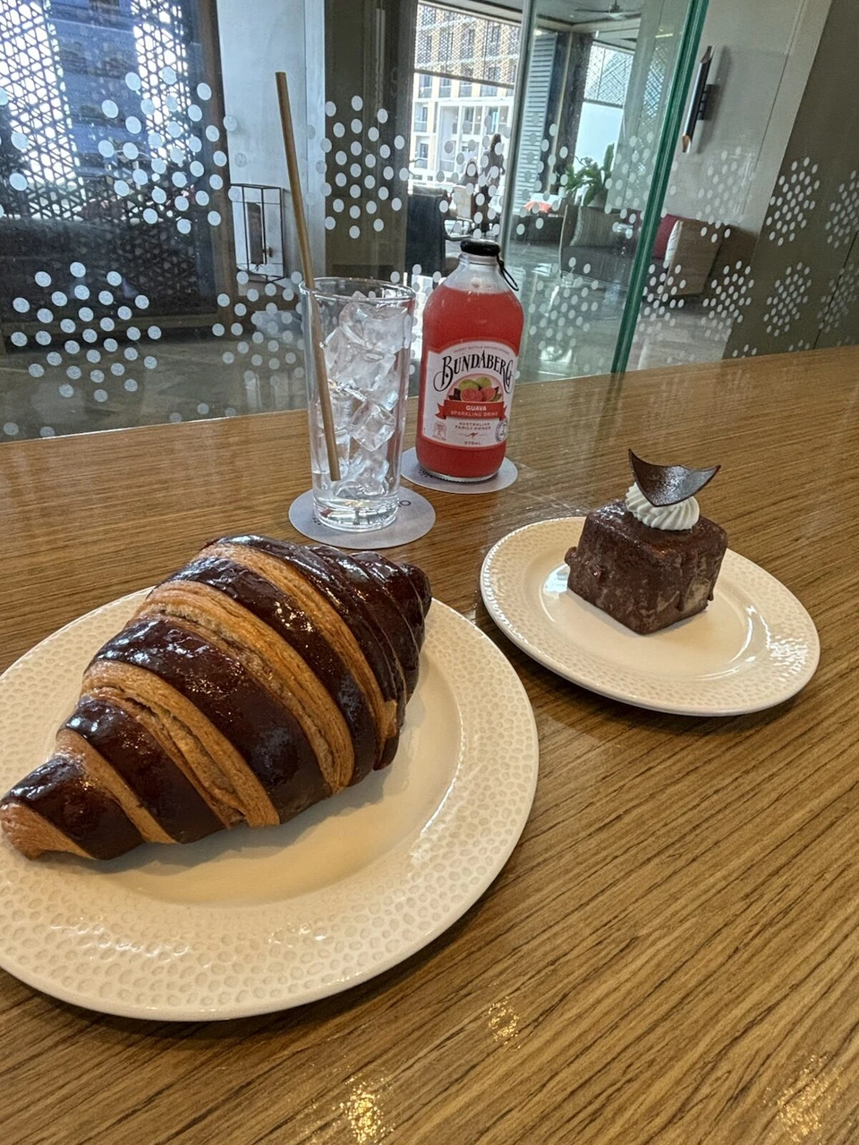ガラスの仕切りがあるカフェ席に並んだクロワッサンとケーキ