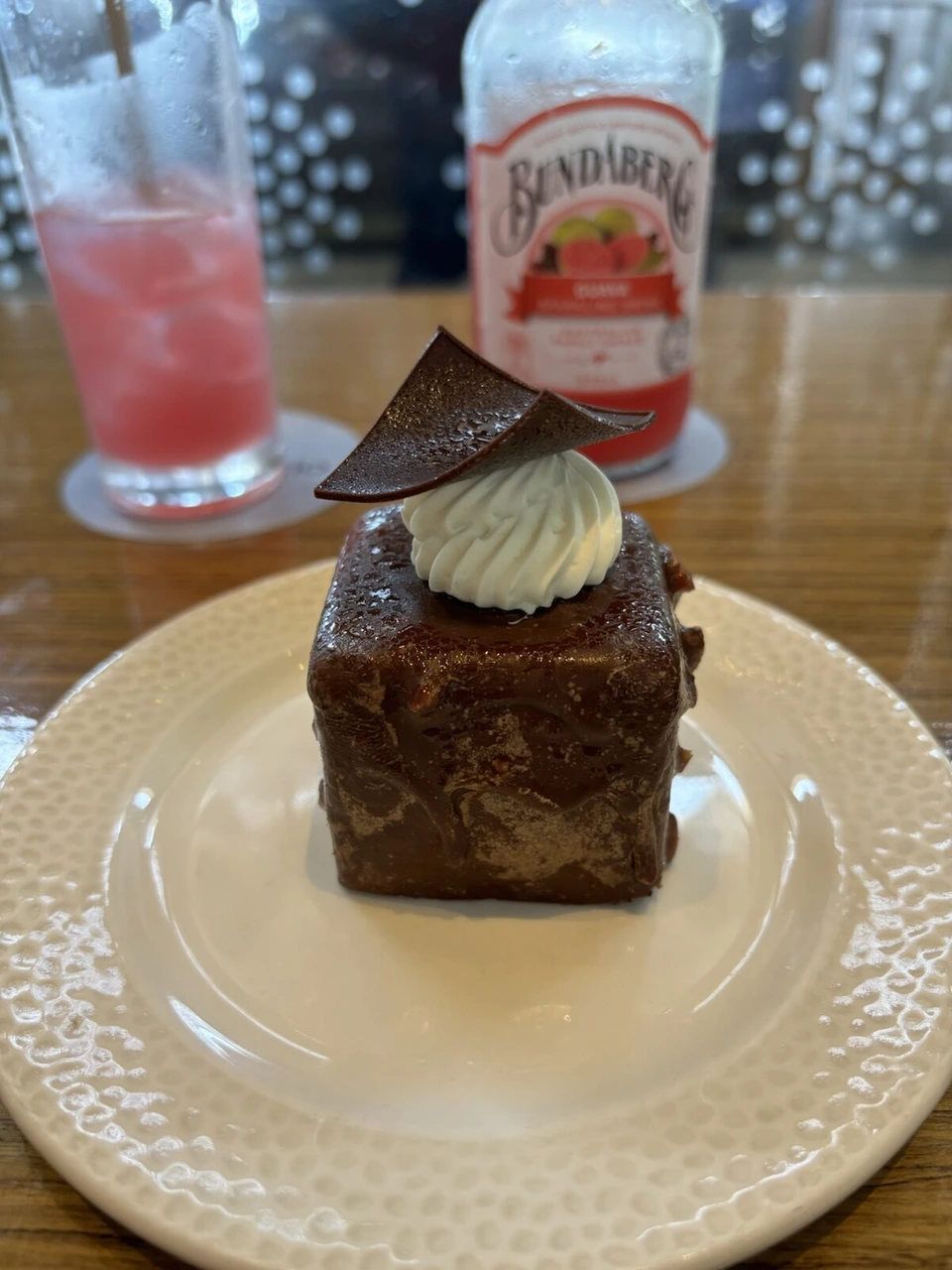 チョコの飾りとクリームをのせた四角いチョコレートケーキ