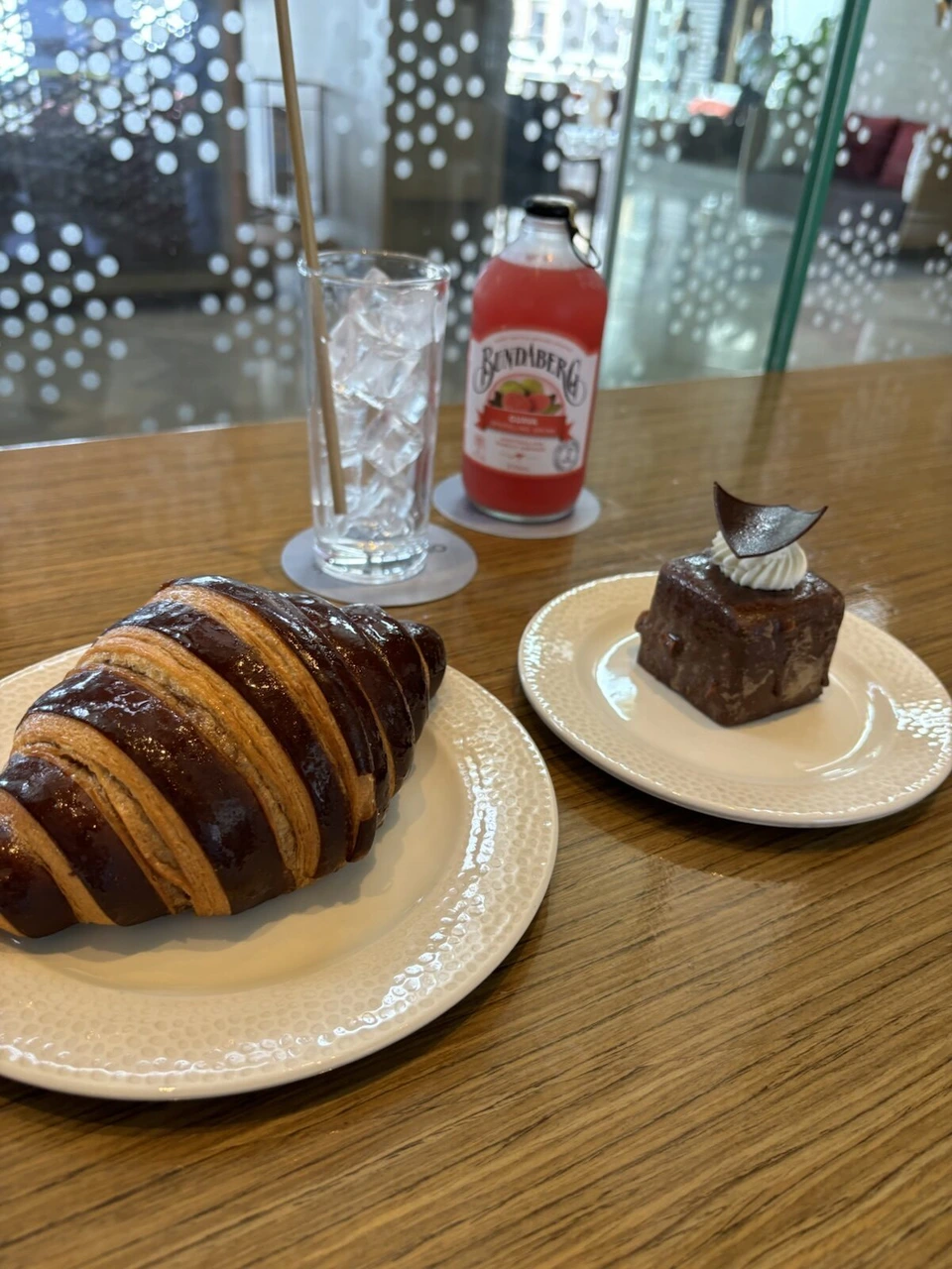 カフェのテーブルにチョコレートのクロワッサン、チョコケーキ、ブンダバーグのピンクグレープフルーツ