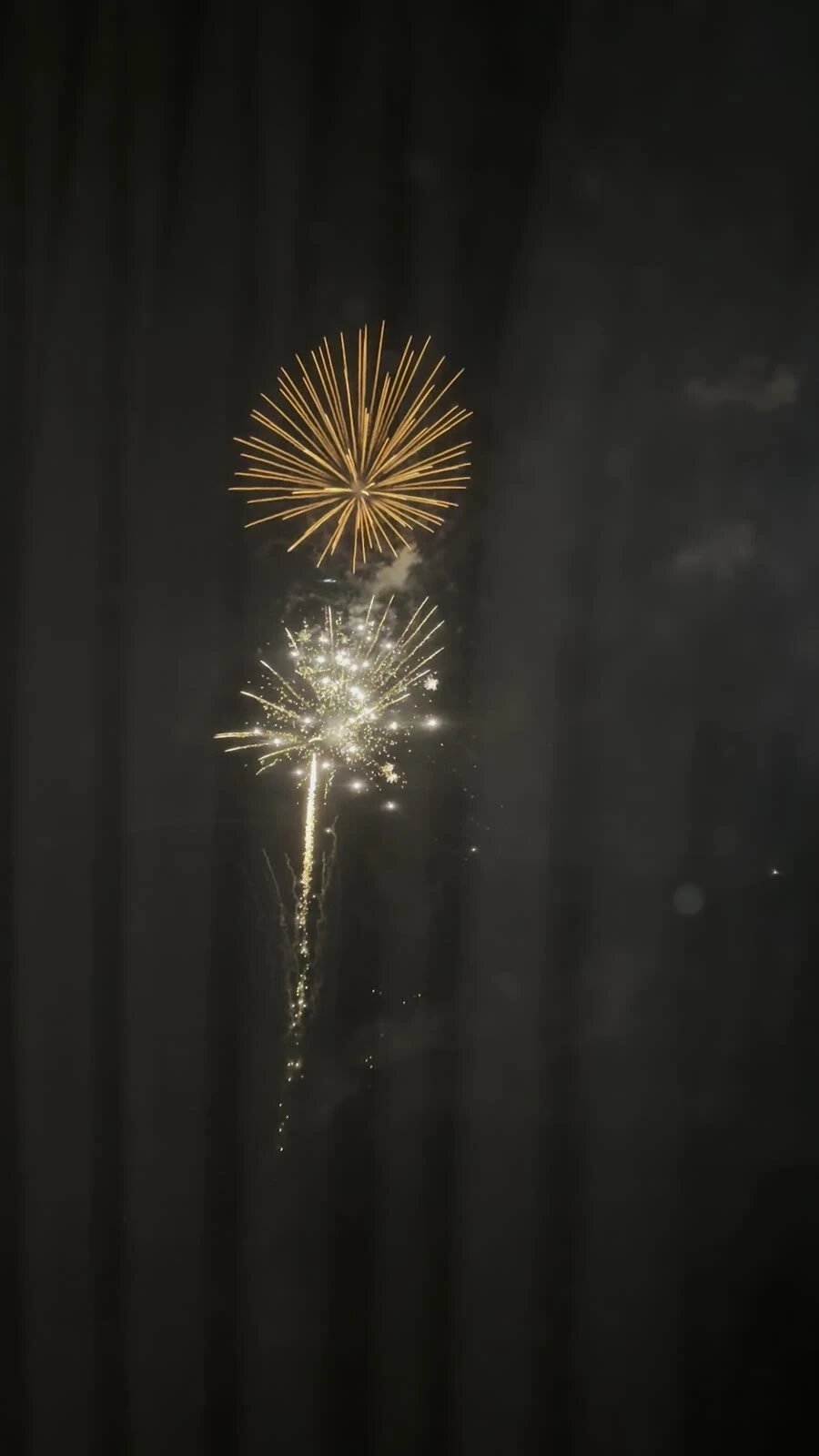 客室の窓越しに見た、金色と白の花火