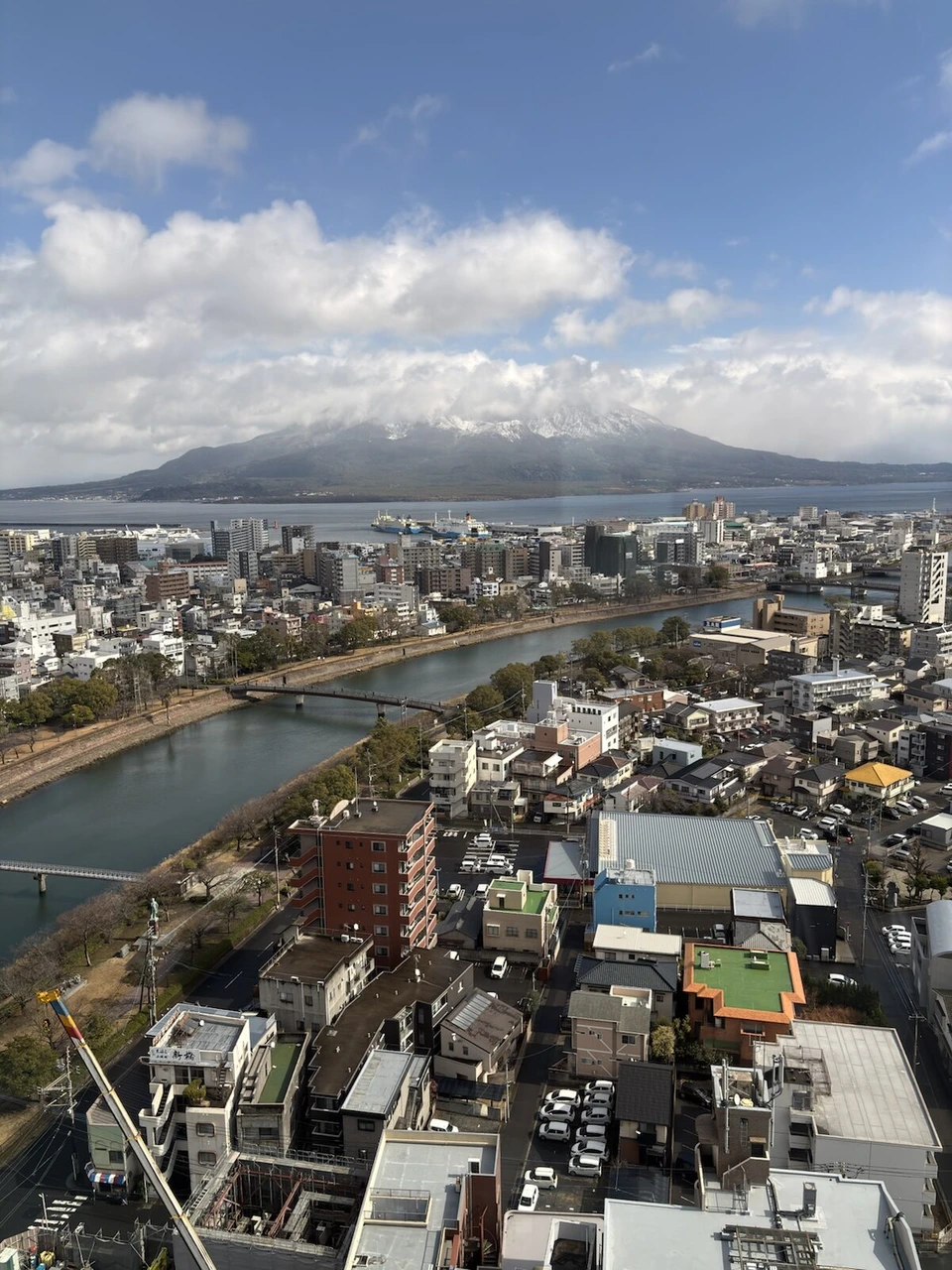 雪がやんだあとの客室の窓から見た桜島と甲突川、鹿児島の街並み