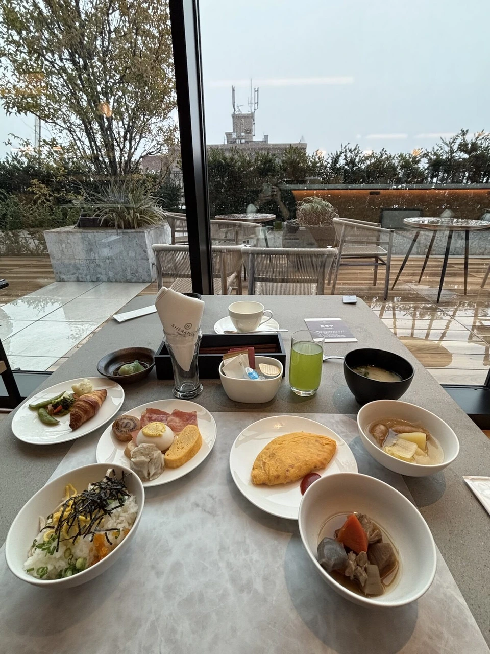 シェラトン鹿児島の朝食。オムレツ、ちらし寿司風のご飯、煮物、パン、味噌汁。窓の外にテラス