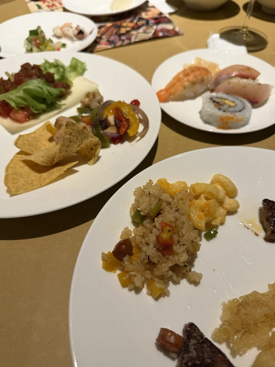 テーブルに並んだビュッフェの皿。寿司、ピラフとマカロニチーズ、肉料理