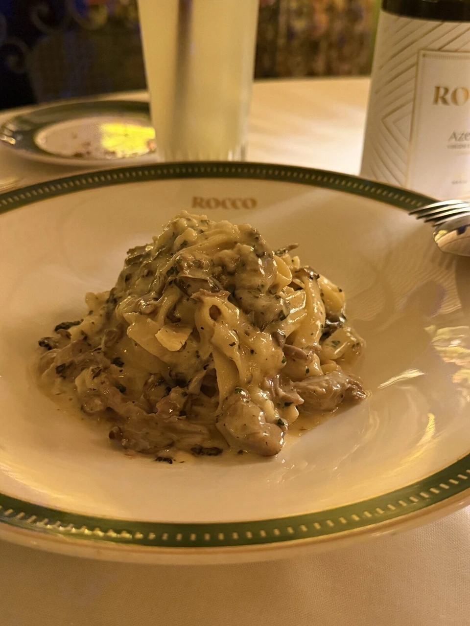 ROCCOの皿に盛られた、きのこの入ったクリーミーな平打ちパスタ
