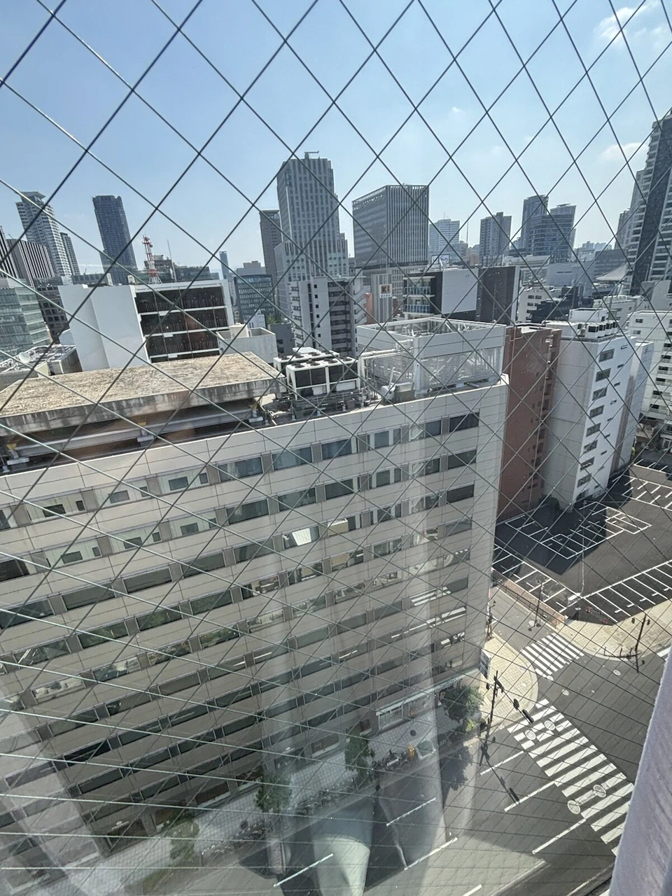 向かいのビルの屋上と、その奥に並ぶ高層ビル