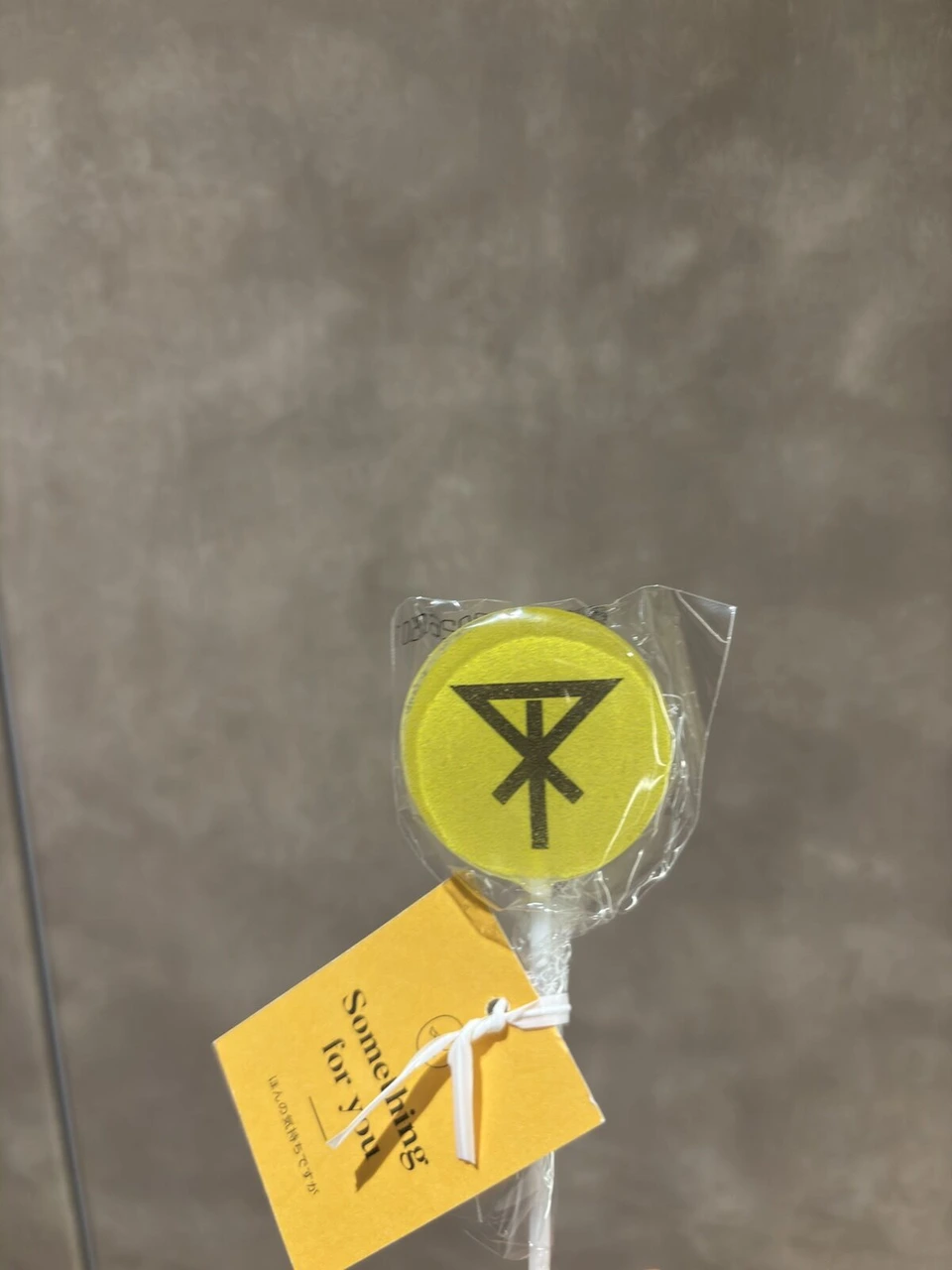 黄色い棒付きキャンディと、Something for youと書かれた黄色いタグ