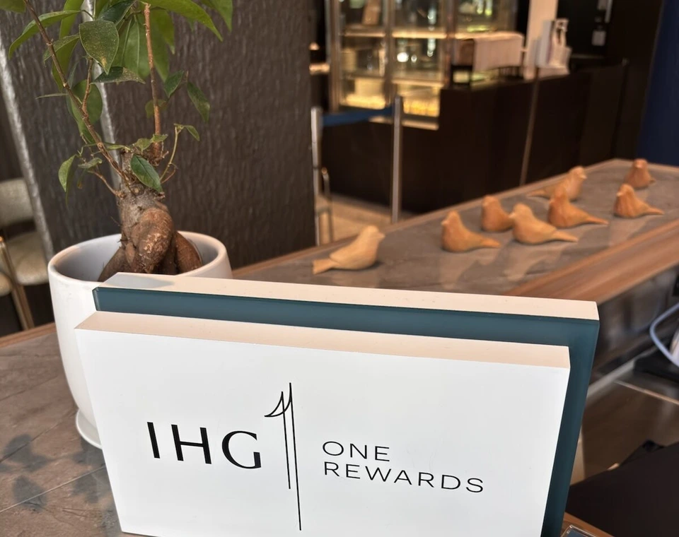フロントのカウンターに置かれたIHG ONE REWARDSのサインと、木彫りの小鳥の置き物