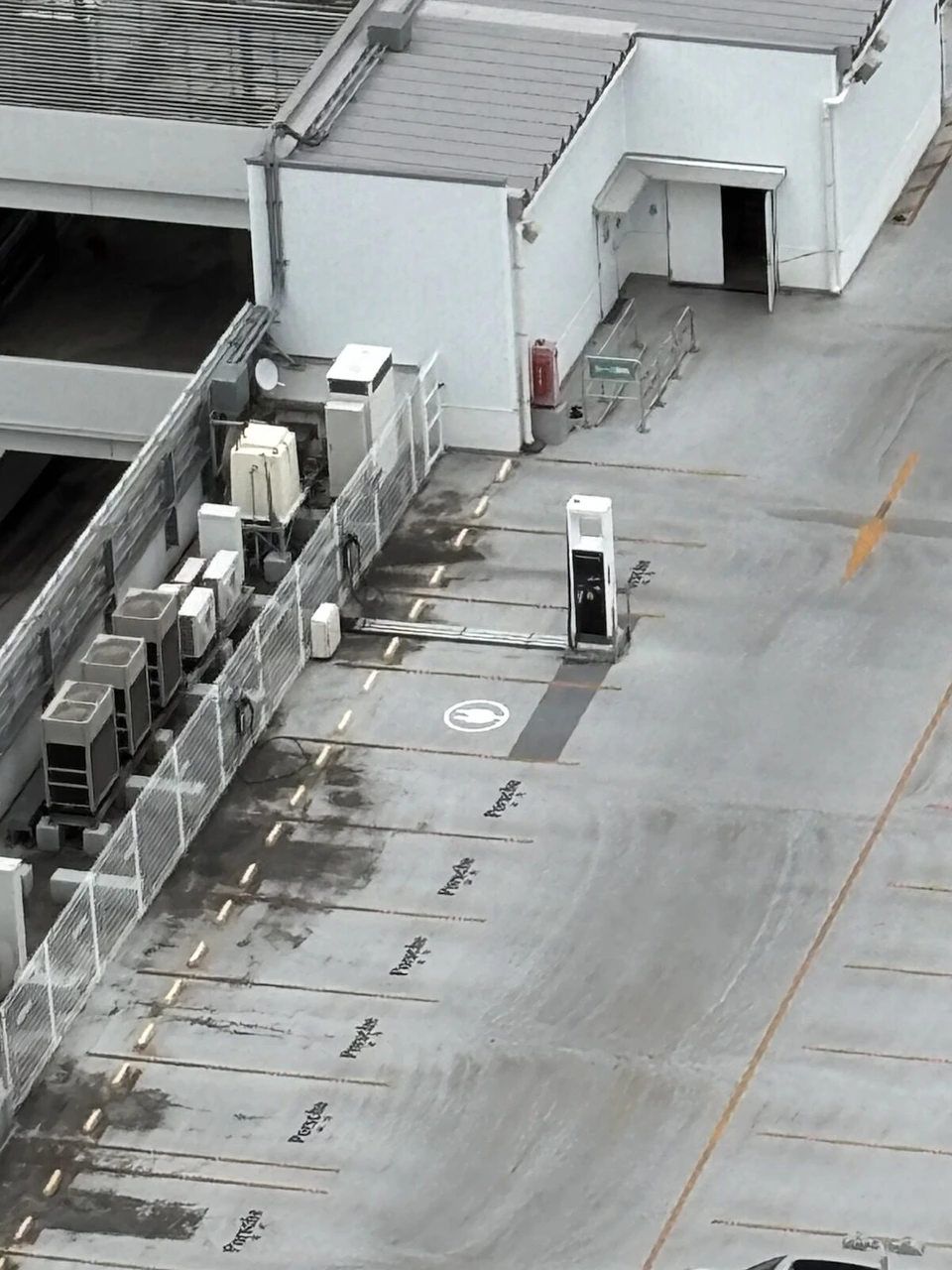 客室から見下ろした立体駐車場の屋上。Porscheの文字が並ぶ駐車枠と充電器