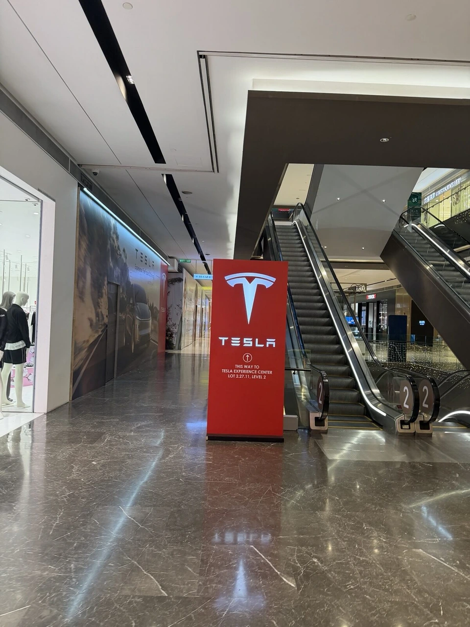 クアラルンプールのショッピングモールの通路に立つテスラの赤い案内板。Experience Center Level 2