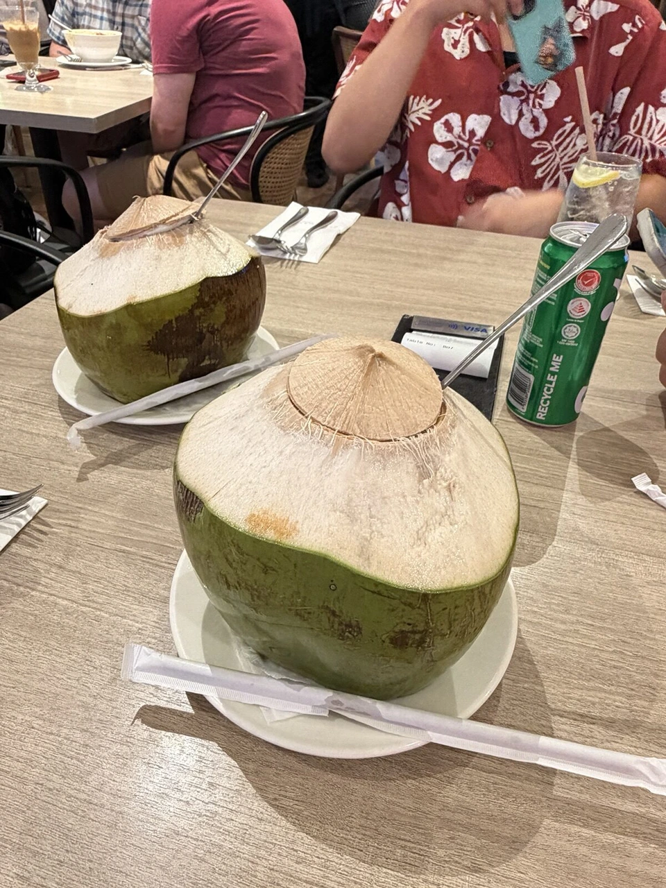 テーブルに並んだ丸ごとのヤシの実のココナッツジュースと缶の飲み物