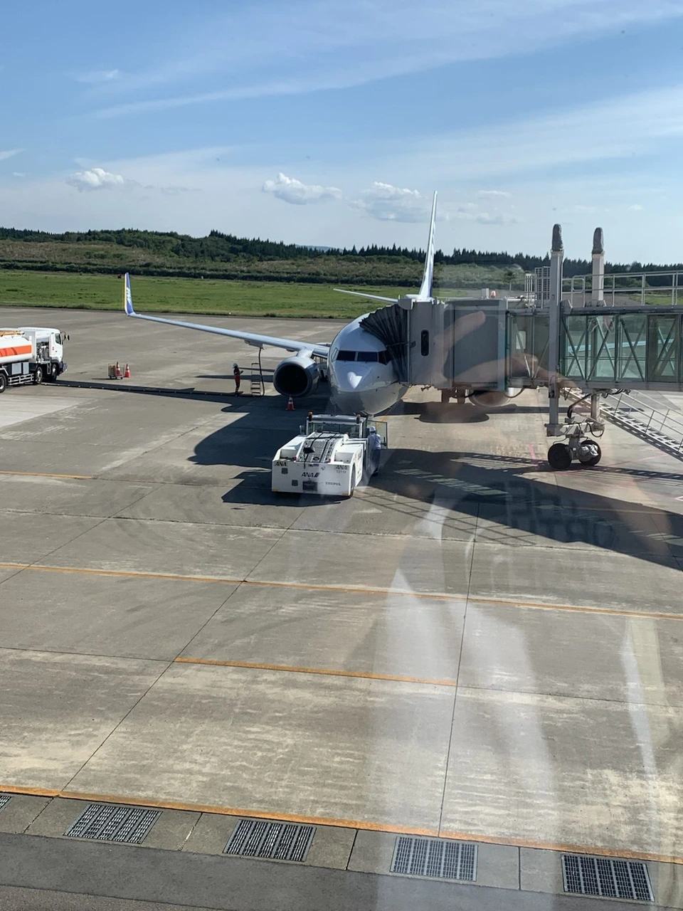 大館能代空港の駐機場でボーディングブリッジにつながったANAの737-800と、トーイングカーや給油車