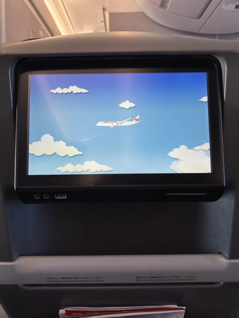 JL525の座席モニター。青空と雲の中を飛ぶJAL機のイラスト