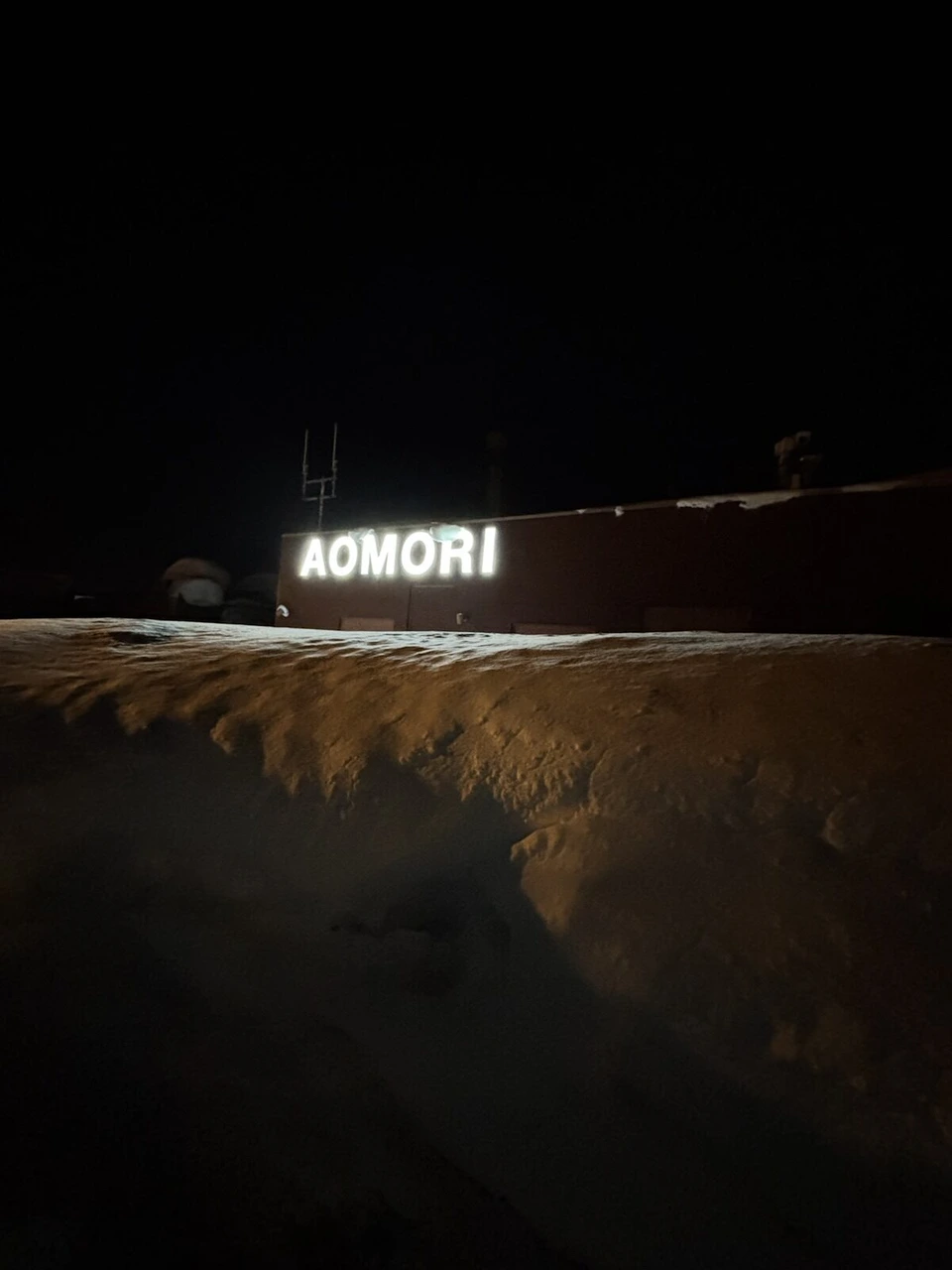 夜の青森空港のAOMORIの文字と雪