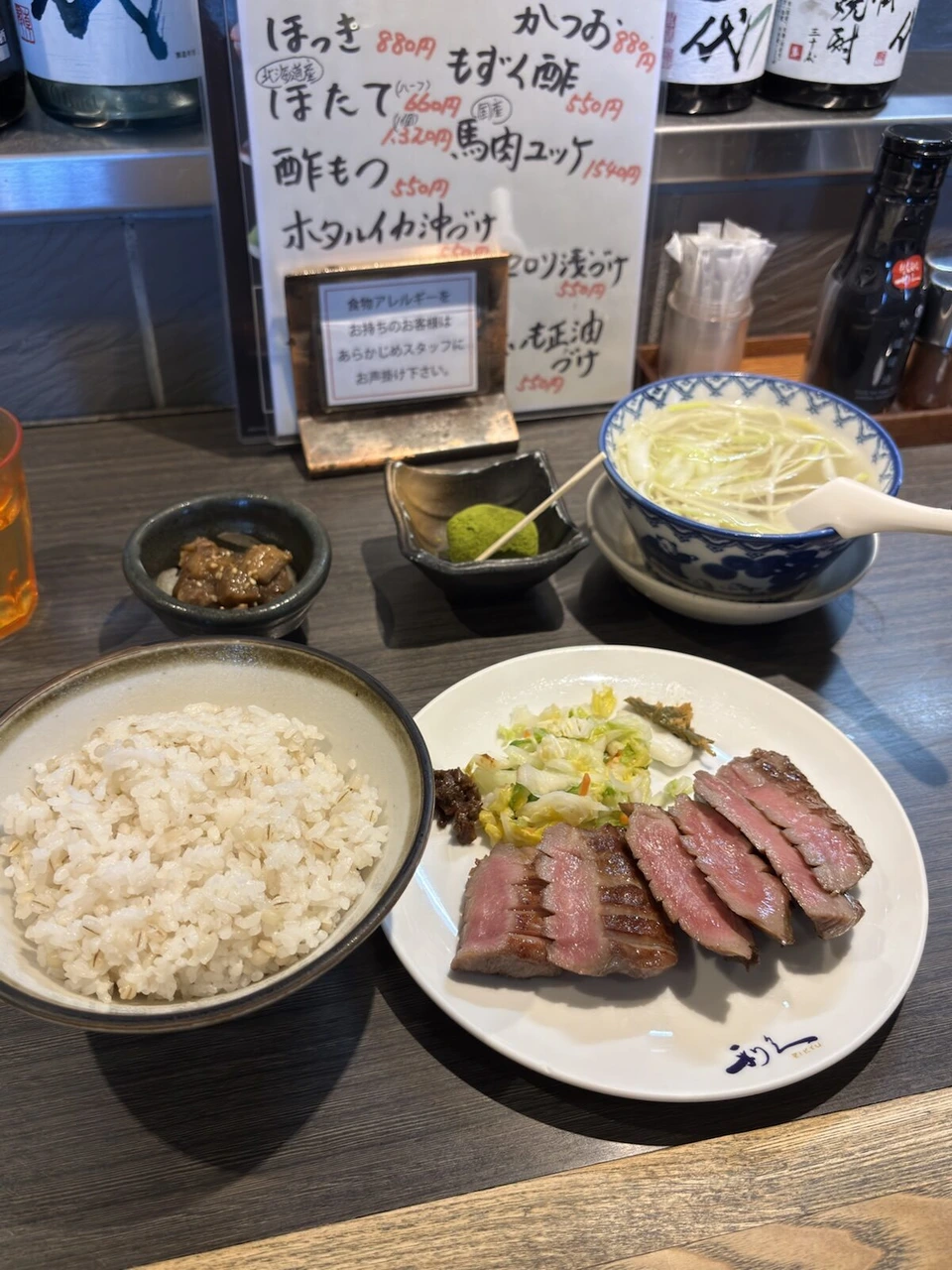 仙台港の近くで食べた牛たん焼きの定食。麦ごはん、テールスープ、南蛮味噌、小鉢。奥に手書きのおすすめメニュー
