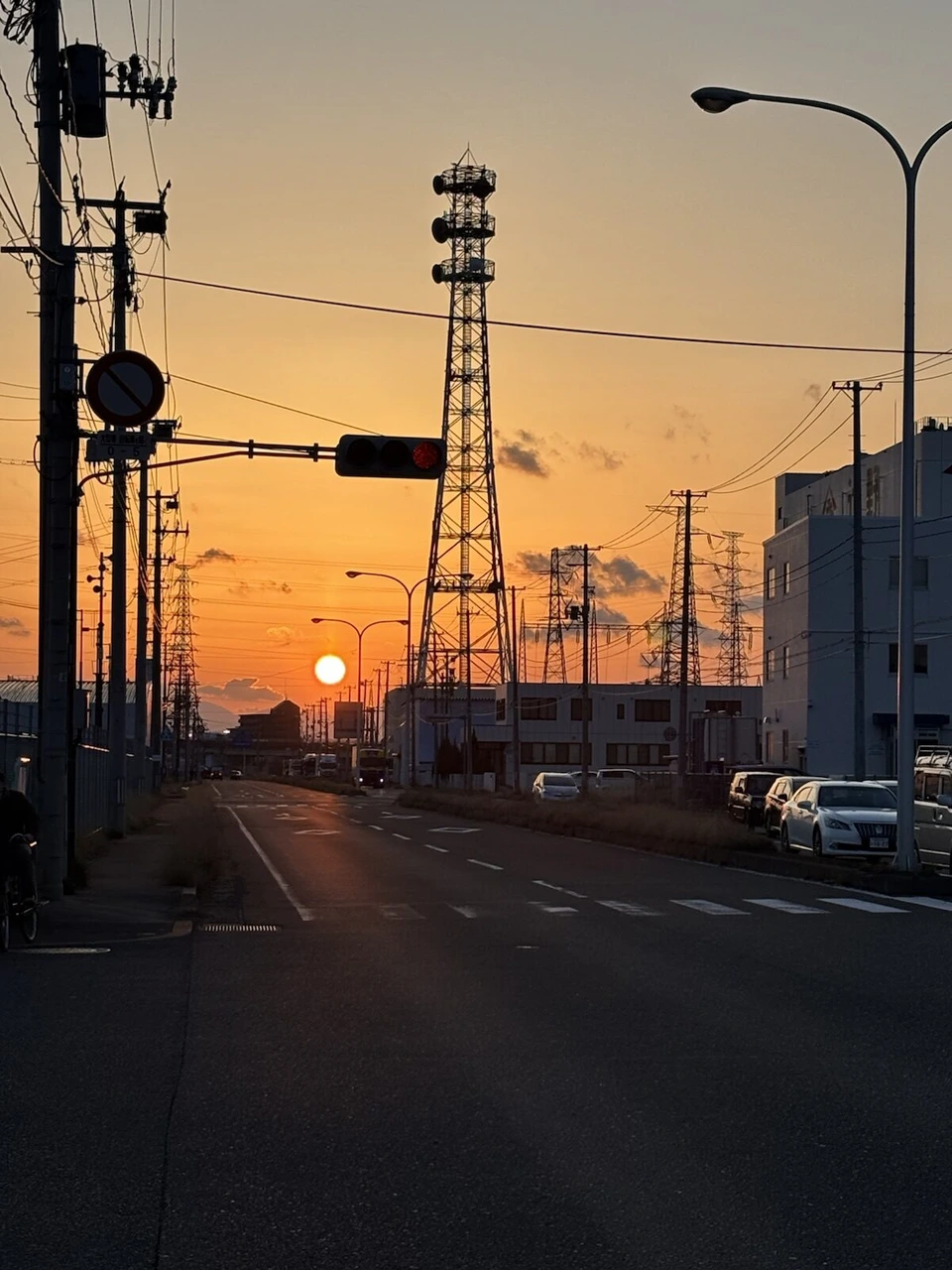 仙台港近くの道路の先に沈む夕日と鉄塔、電線
