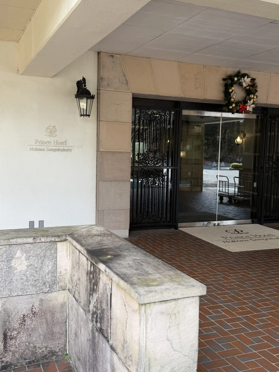 箱根仙石原プリンスホテルの入口。Prince Hotel Hakone Sengokuharaのロゴの壁、クリスマスリースが飾られたガラスの扉