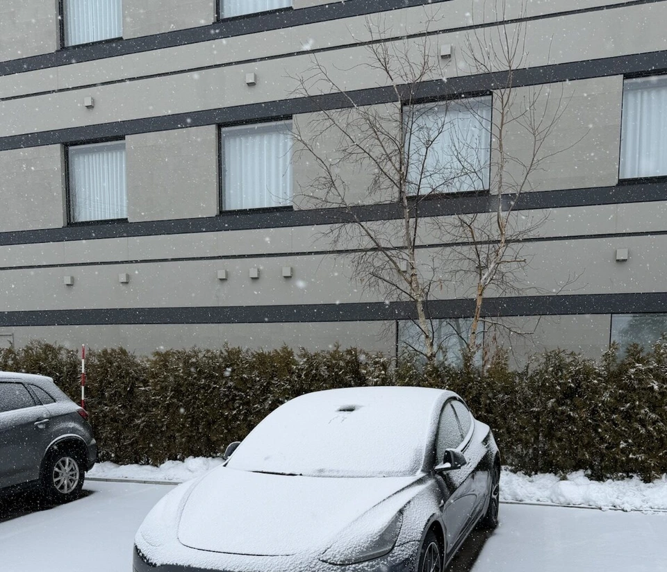 フェアフィールド北海道長沼の建物の前の駐車場で、雪をかぶったテスラ