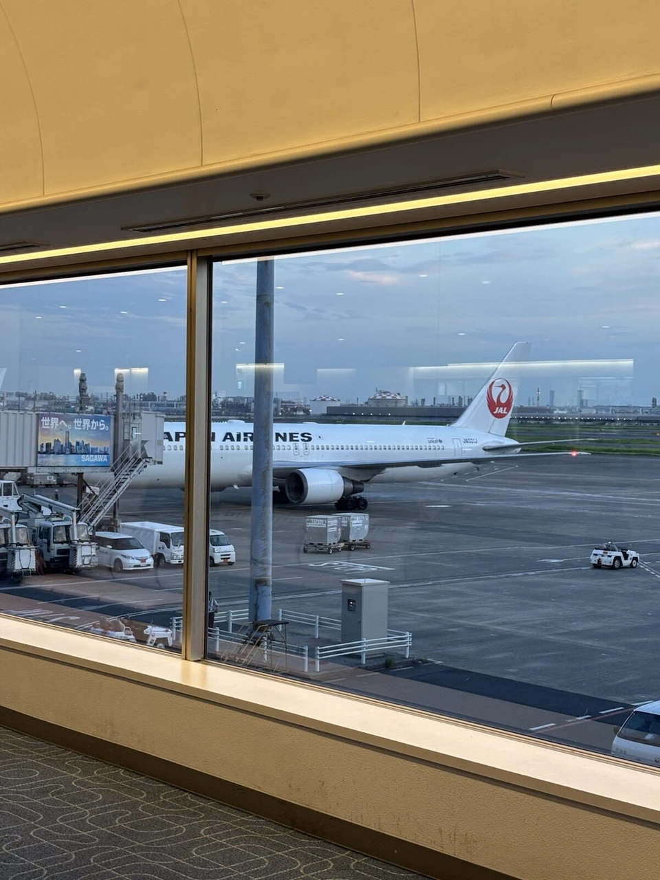 羽田空港第1ターミナルの窓越しに見た、夕方の駐機場に止まるJALのボーイング767