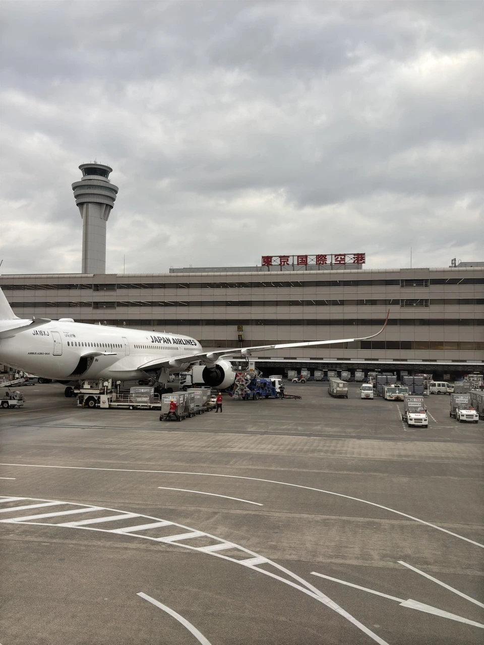 羽田空港第1ターミナルの建物と管制塔、手前の駐機場に止まるJAL機