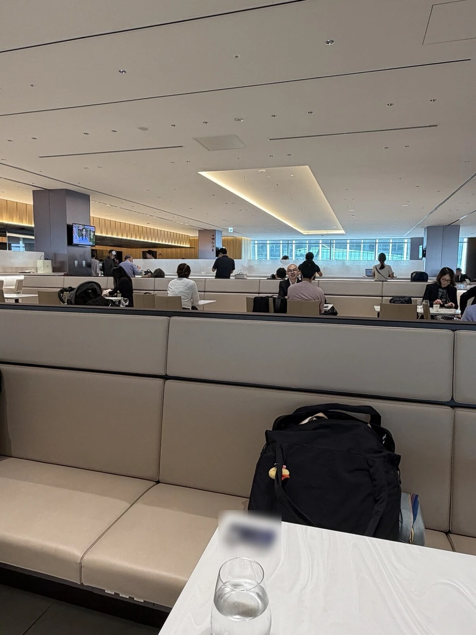 羽田空港第2ターミナル国際線のANA LOUNGE。手前にベージュのソファ席と白いテーブル、奥に窓際の席が並ぶ
