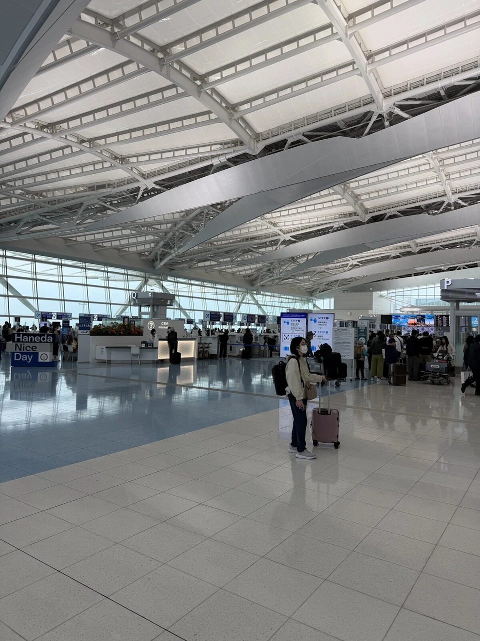 朝の羽田空港第2ターミナル国際線の出発ロビー。白い大きな屋根の骨組みの下に、チェックインカウンターと歩く人