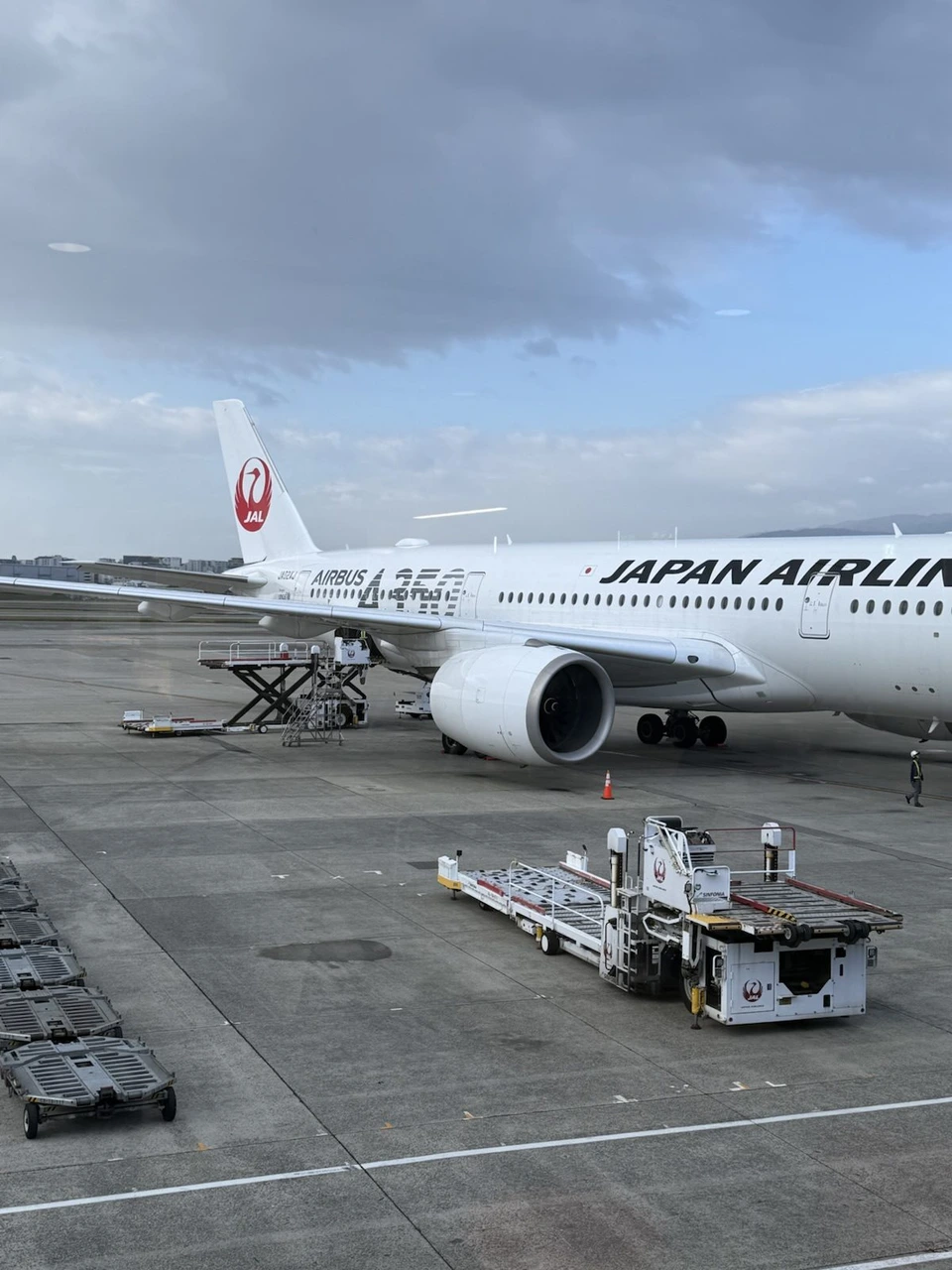 伊丹空港のスポットに止まるJALのエアバスA350と、地上の作業車